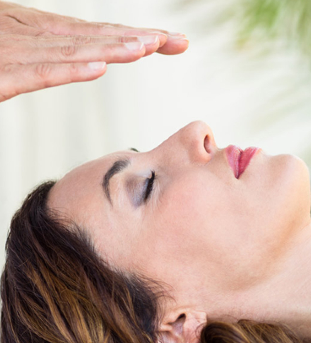 Peaceful young woman receiving reiki healing treatment in the health spa